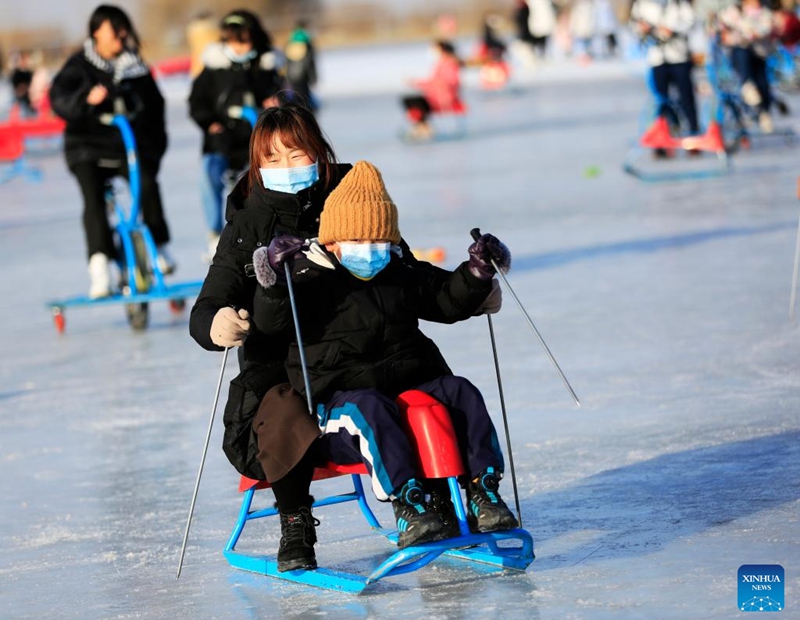 People have fun on an ice rink in Zhangye, northwest China's Gansu Province, Jan. 1, 2023. (Photo by Chen Li/Xinhua)