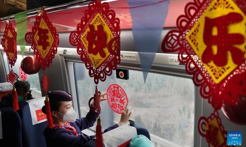 An attendant pastes paper-cut window decoration on the train G2023 running from Shangqiu in central China's Henan Province to Lanzhou in northwest China's Gansu Province, Jan. 1, 2023. Various activities to celebrate the new year were held on the train G2023 as the number of the train coincides with the year of 2023. (Xinhua/Li An)