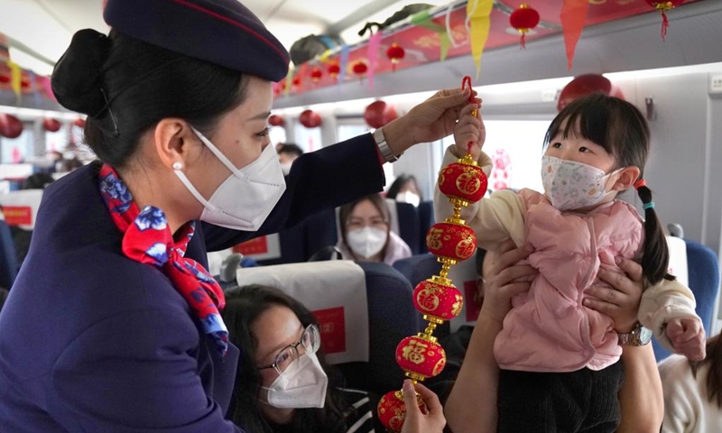 An attendant of train G2023 interacts with a child on the train running from Shangqiu in central China's Henan Province to Lanzhou in northwest China's Gansu Province, Jan. 1, 2023. Various activities to celebrate the new year were held on the train G2023 as the number of the train coincides with the year of 2023. (Xinhua/Li An)