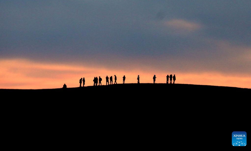 Tourists visit Mingsha Mountain and Crescent Spring scenic spot in Dunhuang City, northwest China's Gansu Province, Jan. 1, 2023. (Photo by Zhang Xiaoliang/Xinhua)