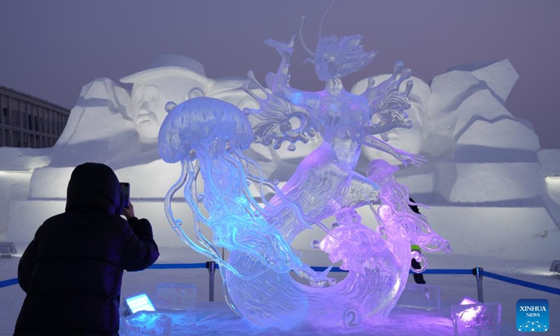 A tourist takes pictures of a price-winning ice sculpture at the Harbin Ice-Snow World theme park in Harbin, northeast China's Heilongjiang Province, Jan. 6, 2023. A competition, featuring ice sculptures with exquisite craftsmanship from 12 sculptor teams, concluded here on Saturday. (Xinhua/Wang Jianwei)