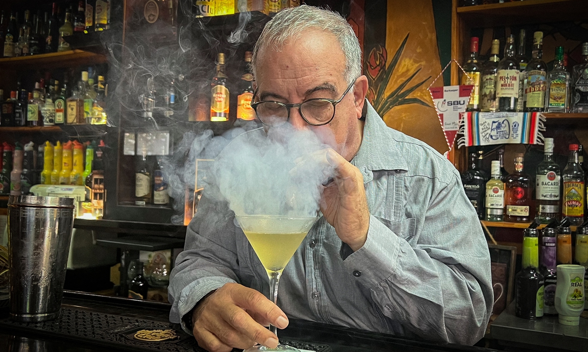 Master bartender Jose Rafa Malen blows tobacco smoke toward an original daiquiri (without ice) at the Bartenders Association in Havana, Cuba. File photo: AFP