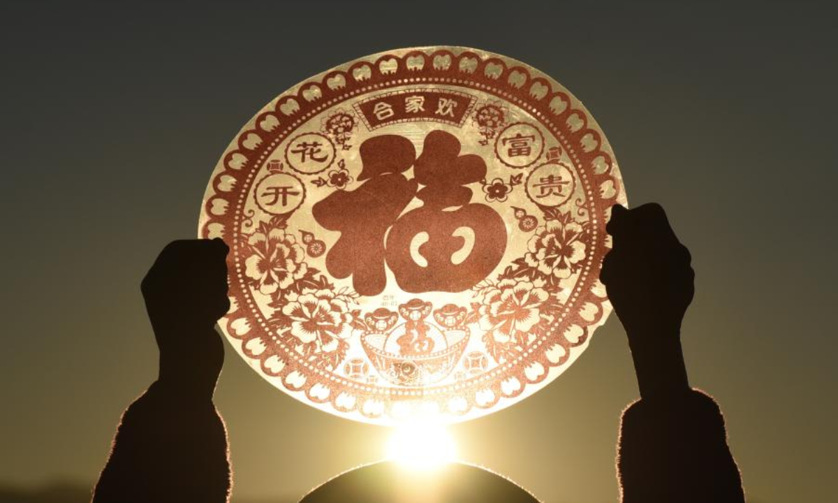 A villager holds up a decoration with the Chinese character 