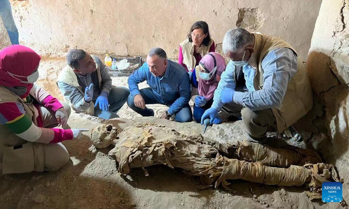 The undated photo shows archeological workers gathering around a mummy unearthed at an ancient family tomb in Luxor, Egypt. Photo:Xinhua