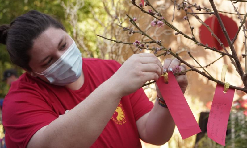 A woman attaches a note of wishes on the wish tree at San Diego Zoo, in San Diego, California, the United States, on Feb. 4, 2023. The San Diego Zoo, which has the largest number of annual visitors among U.S. zoos, kicked off a two-day special event on Saturday to celebrate the Chinese New Year. Photo: Xinhua