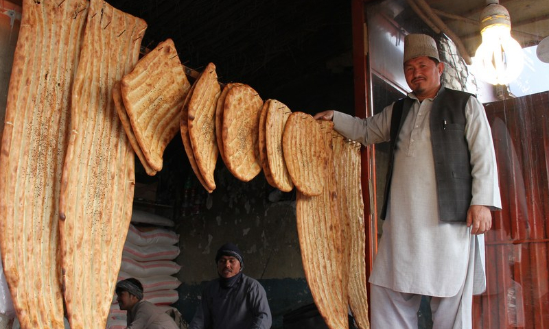 A man poses for photos with naan bread for sale at a bakery in Balkh Province, Afghanistan on Jan. 24, 2023.  Photo: Xinhua