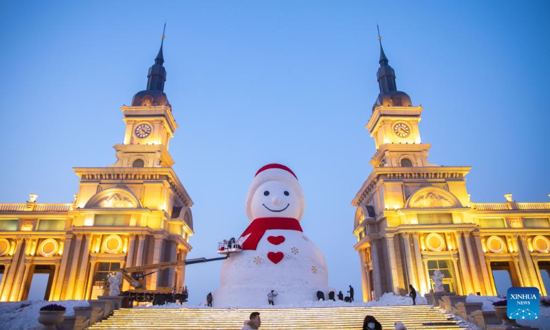 Workers do finishing work of the giant snowman near the Songhua river in Harbin, northeast China's Heilongjiang Province, Jan. 4, 2023. The giant snowman, 18 meters in height and made with 2,000 cubic meters of snow, becomes a landmark of Harbin. (Xinhua/Zhang Tao)
