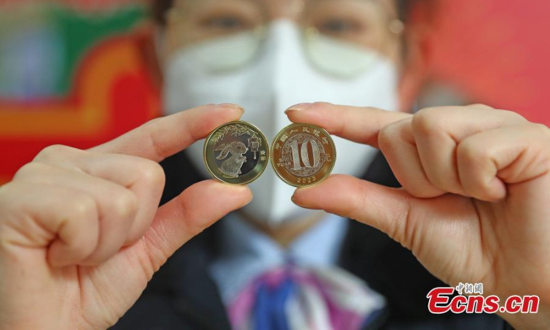A staff member displays the commemorative coins for the Year of the Rabbit at the Jiangxi branch of the Postal Saving Bank of China in Nanchang, east China's Jiangxi Province, Jan. 5, 2023. (Photo: China News Service/Liu Zhankun)