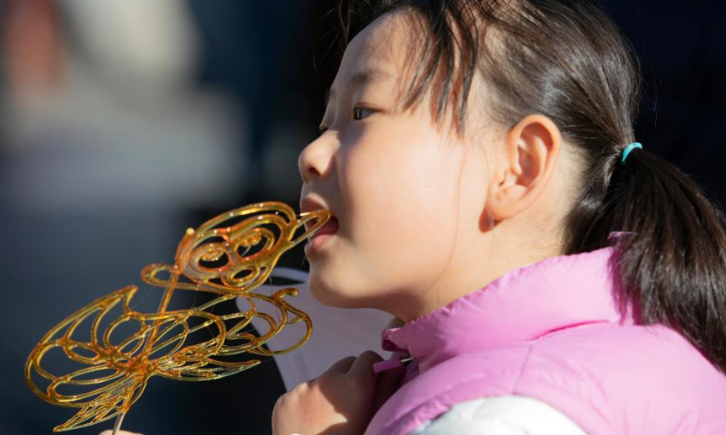 A child enjoys food at the Nanluoguxiang Lane in Beijing, capital of China, Jan. 27, 2023. People enjoy the last day of the Spring Festival holiday on Friday. Photo: Xinhua