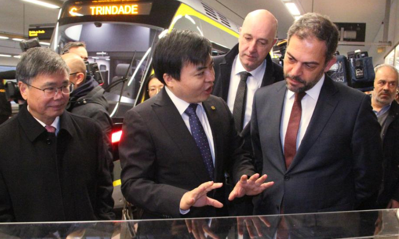Tan Mu (C, front), general manager of CRRC Tangshan, illustrates China-made metro trains over a model as Portuguese Minister of Environment and Climate Action Duarte Cordeiro (R, front) and Chinese Ambassador to Portugal Zhao Bentang (L, front) listen inside the Trindade Metro Station at the center of Porto, Portugal, Feb. 11, 2023. First of the 18-set metro trains made by Chinese company was delivered to the Porto Metro company of Portugal on Saturday. Photo: Xinhua