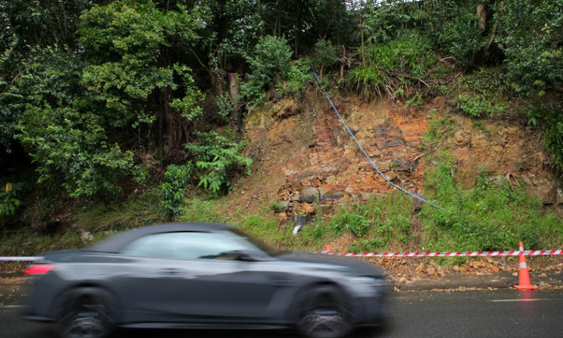 A car drives by a landslide section of the road in Auckland, New Zealand, Feb. 12, 2023. Twenty severe weather warnings and watches are in place as tropical cyclone Gabrielle is landing far north of New Zealand and is expected to swipe through most parts of the North Island from Sunday. Photo: Xinhua