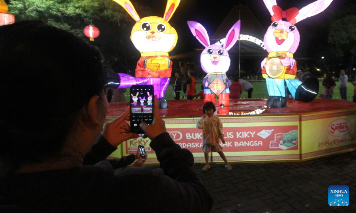 A girl poses for a photo in front of lantern decorations celebrating the Chinese Lunar New Year in Surakarta, Central Java, Indonesia, Jan 19, 2023. Photo:Xinhua