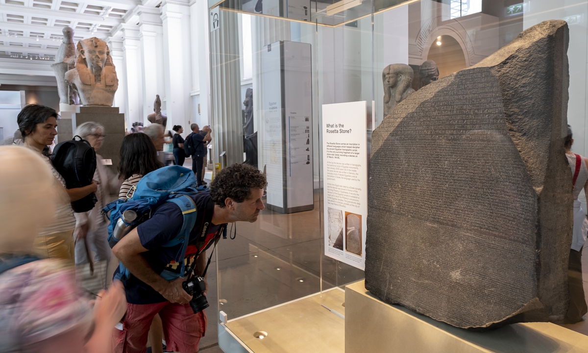 A visitor examines the Egyptian Rosetta Stone at the British Museum in London. Photo: VCG