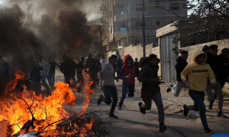 People run to take cover during clashes with Israeli forces in the West Bank city of Jenin, on Jan. 26, 2023. Israeli forces killed on Thursday at least nine Palestinians, including an elderly woman, during a raid in the occupied West Bank, Palestinian sources said, amid escalating violence in the region. Photo: Xinhua