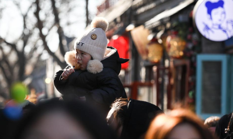 A child enjoys food at the Nanluoguxiang Lane in Beijing, capital of China, Jan. 27, 2023. People enjoy the last day of the Spring Festival holiday on Friday. Photo: Xinhua