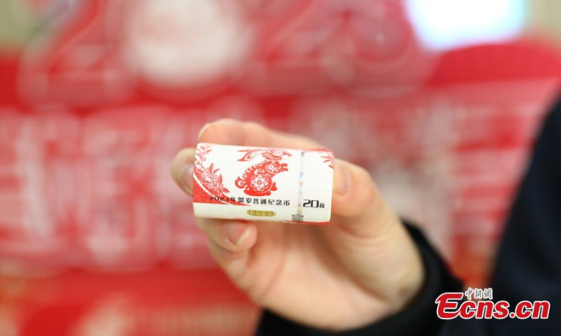 A staff member displays a set of commemorative coins for the Year of the Rabbit in the Jiangxi branch of Postal Saving Bank of China in Nanchang, east China's Jiangxi Province, Jan. 5, 2023. (Photo: China News Service/Liu Zhankun)