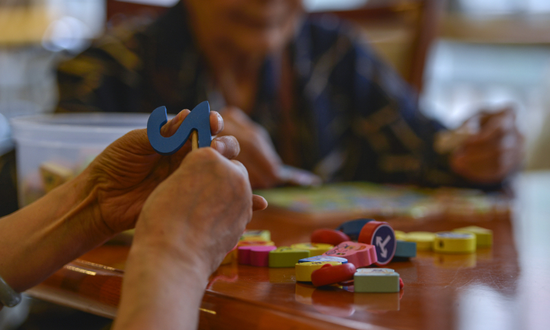 An elderly patient is playing with intellectual toys on June 17, 2015 in a nursing home for patients with Alzheimer's disease in Chaoyang district, Beijing. Photo: VCG