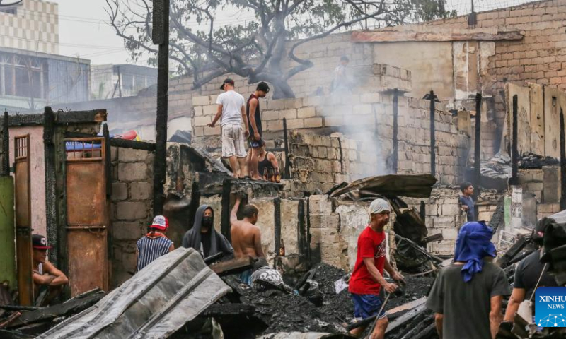 Residents are seen on the rubbles of their homes after a fire at a residential area in Quezon City, the Philippines, Feb. 19, 2023. Photo: Xinhua