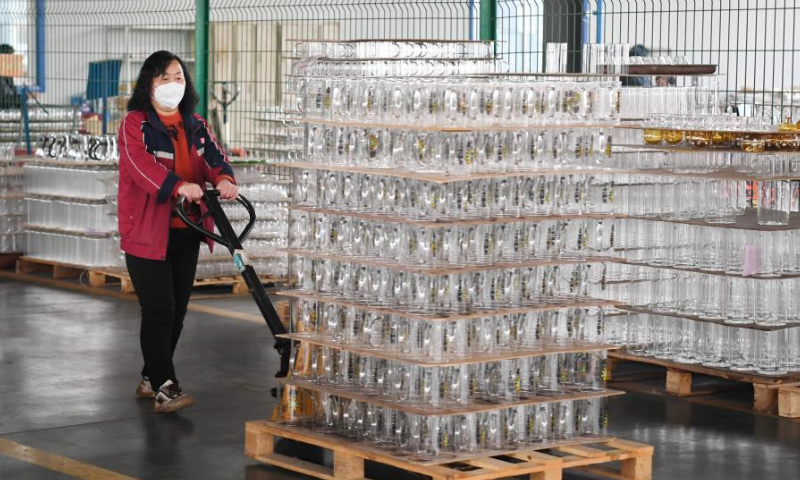 A worker carries glasswork at the workshop of a company in Hejian City, north China's Hebei Province, Feb. 11, 2023. Hejian City is famous for its glasswork making industry. Now, there are more than 200 glasswork making companies and over 60,000 staff members involved in the industry in Hejian. The annual output of the glasswork reached nearly 10 billion yuan (about 1.47 billion U.S. dollars) and the glasswork has been exported to over 50 countries and regions. Photo: Xinhua