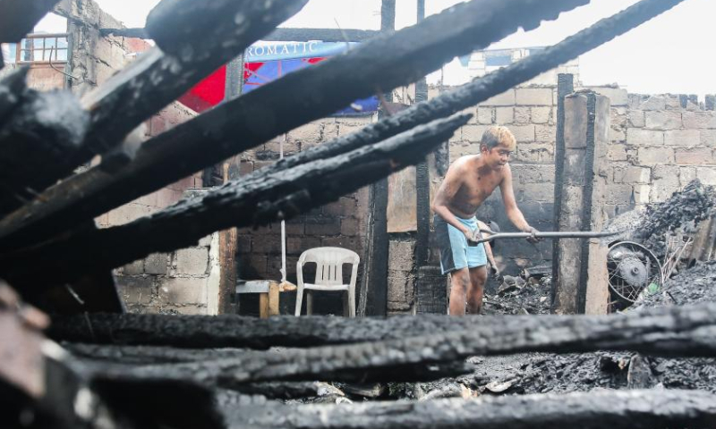 A resident clears charred remains of a house after a fire at a residential area in Quezon City, the Philippines, Feb. 19, 2023. Photo: Xinhua