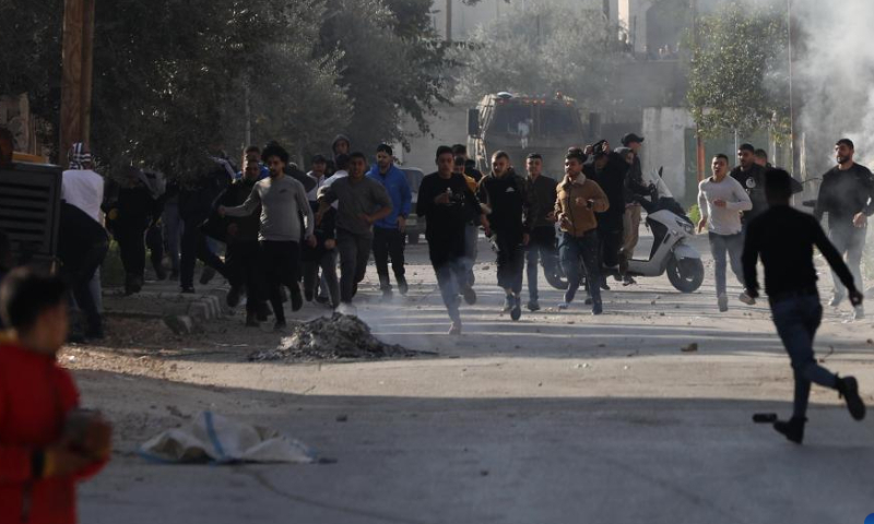 People run to take cover during clashes with Israeli forces in the West Bank city of Jenin, on Jan. 26, 2023. Israeli forces killed on Thursday at least nine Palestinians, including an elderly woman, during a raid in the occupied West Bank, Palestinian sources said, amid escalating violence in the region. Photo: Xinhua