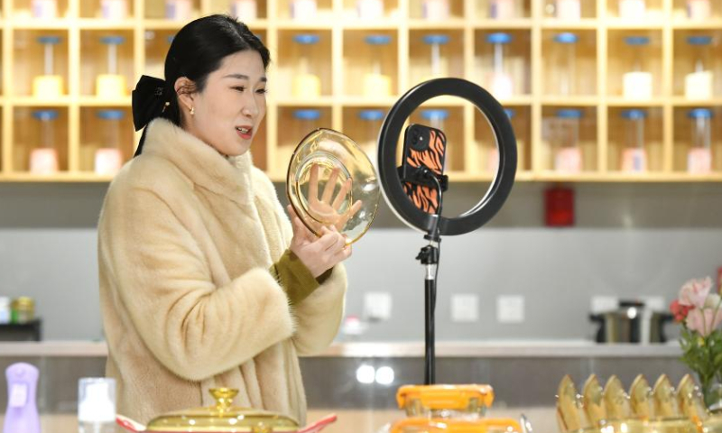 A staff member presents glasswork via livestreaming at a company in Hejian City, north China's Hebei Province, Feb. 11, 2023. Hejian City is famous for its glasswork making industry. Now, there are more than 200 glasswork making companies and over 60,000 staff members involved in the industry in Hejian. The annual output of the glasswork reached nearly 10 billion yuan (about 1.47 billion U.S. dollars) and the glasswork has been exported to over 50 countries and regions. Photo: Xinhua
