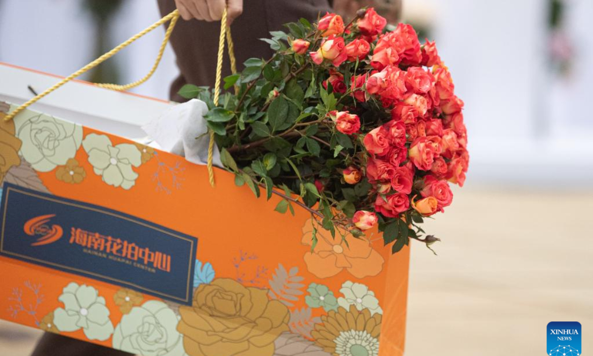 This photo taken on Jan 18, 2023 shows a customer carrying a bunch of flowers shopped at the Hainan Tropical Flower Trading (Auction) Market in Haikou, south China's Hainan Province. Photo:Xinhua