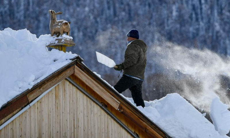 A villager removes snow on the roof in Hemu Village in the Altay Mountains in northwest China's Xinjiang Uygur Autonomous Region, Jan. 14, 2023. Xinjiang, which boasts favorable natural conditions and multiple high-standard ski resorts, has taken the starring role in the booming industry to become one of the country's most popular winter tourism destinations. Photo: Xinhua