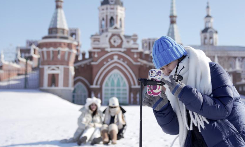 A tourist takes photos at the Volga Manor in Harbin, northeast China's Heilongjiang Province, Jan. 26, 2023. The Volga Manor, a Russian culture-themed park, turned into an ice and snow world during the Spring Festival, attracting lots of visitors. Photo: Xinhua