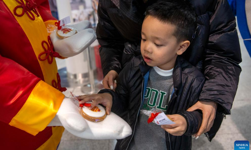 A boy takes a cookie from a staff in rabbit costume at the Athens International Airport in Athens, Greece, Jan. 26, 2023. The Athens International Airport has unveiled the Rabbit Mascot to celebrate the Chinese Lunar New Year of the Rabbit.  Photo: Xinhua