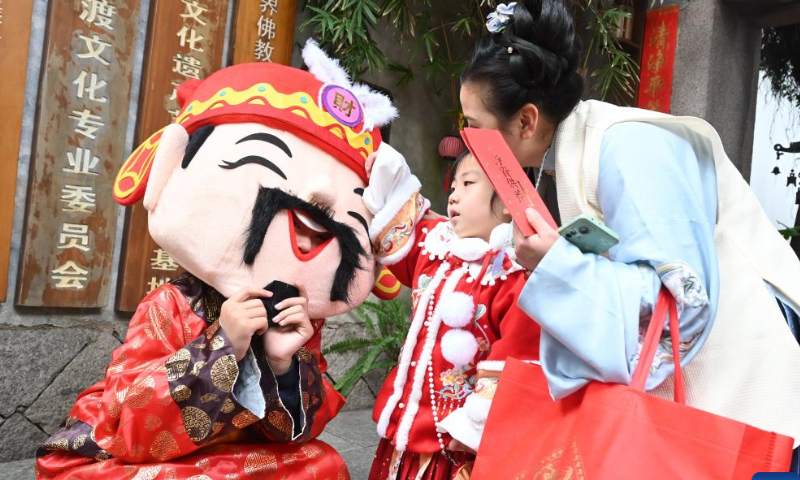 A staff member in the costume of the God of Wealth interacts with tourists at Sanfangqixiang (Three Lanes and Seven Alleys), an ancient block in downtown Fuzhou, southeast China's Fujian Province, Jan. 26, 2023. Ceremonies were held to welcome the God of Wealth as a tradition on the fifth day of the Chinese Lunar New Year, which falls on Thursday this year. Photo: Xinhua