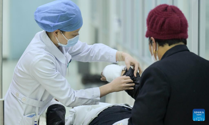 A medical worker checks the condition of a patient at the emergency department of the Second Affiliated Hospital of Anhui Medical University in Hefei, east China's Anhui Province, Jan. 21, 2023. Medical staff stick to their posts during the Spring Festival holiday. (Xinhua/Zhou Mu)
