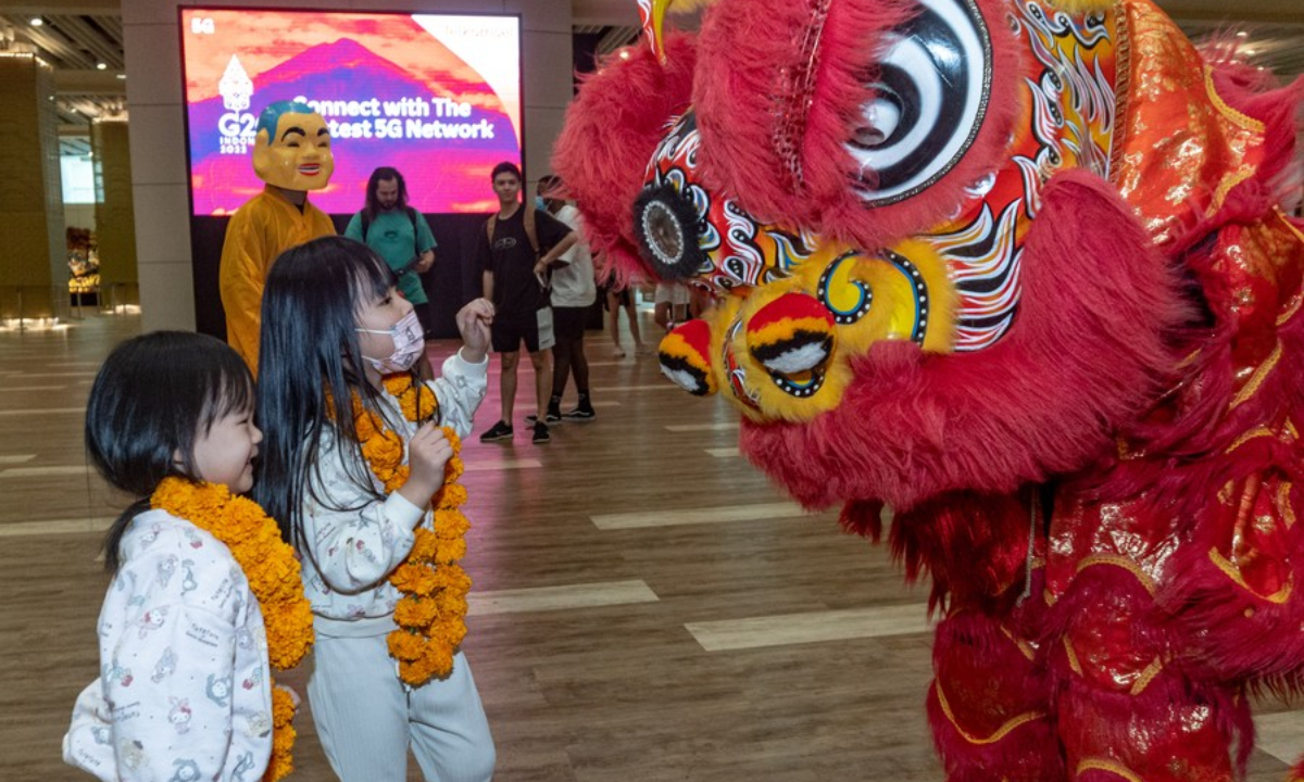 Children interact with a lion dance performer at the Ngurah Rai International Airport in Bali, Indonesia on Jan. 22, 2023. (Photo by Dicky Bisinglasi/Xinhua)
