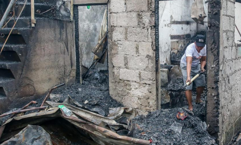 A resident clears charred remains of a house after a fire at a residential area in Quezon City, the Philippines, Feb. 19, 2023. Photo: Xinhua