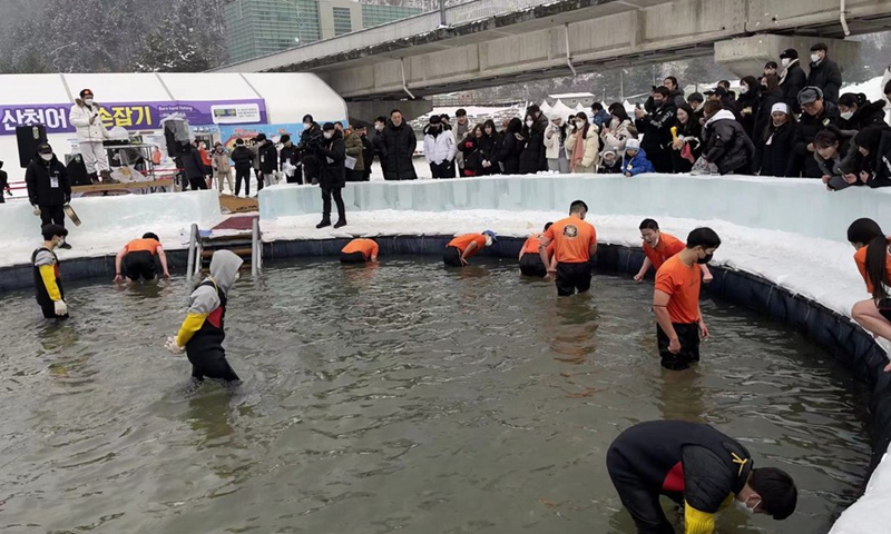 Tourists stand in a lake and snatch fish with bare hands at Hwacheon Sancheoneo Ice Festival in Hwacheon, South Korea, on Jan. 7, 2023. (Xinhua/Sun Yiran)
