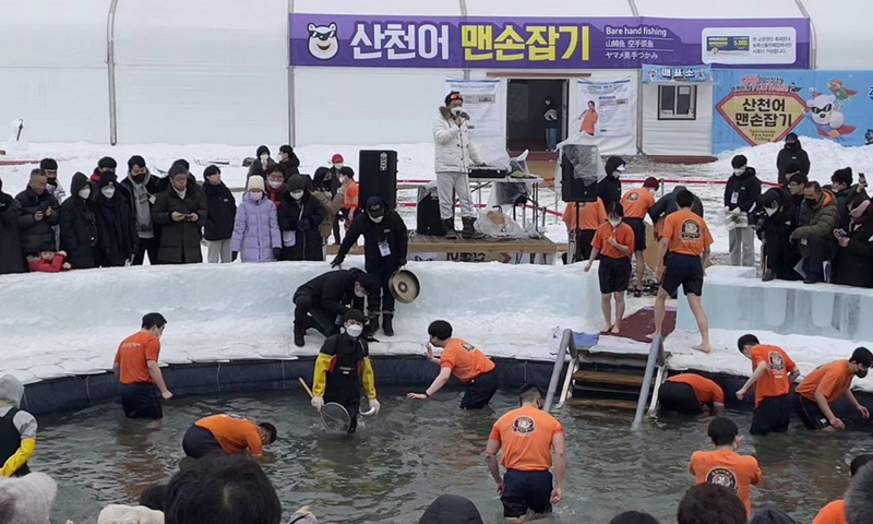 Tourists stand in a lake and snatch fish with bare hands at Hwacheon Sancheoneo Ice Festival in Hwacheon, South Korea, on Jan. 7, 2023. (Xinhua/Sun Yiran)
