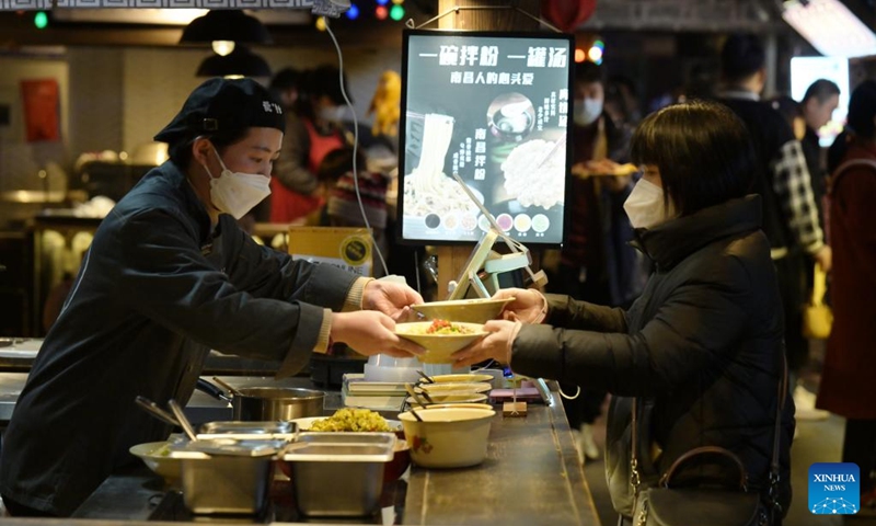 A woman takes food in a restaurant on Leijie street, a commercial area famous for its night economy, in Hefei, east China's Anhui Province, Jan. 6, 2023. The night-time consumption in the commercial area has resumed in an orderly manner recently. (Xinhua/Zhou Mu)