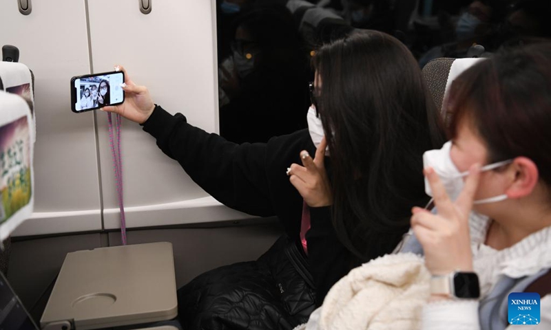 Passengers take selfies aboard train No.G9480 travelling from east China's Shanghai to Bozhou in east China's Anhui Province on the early morning of Jan. 14, 2023. The Hefei branch of China Railway Shanghai Bureau Group Co., Ltd. has added temporary night trains to meet the needs of travellers during the Spring Festival travel rush. (Xinhua/Zhang Duan)