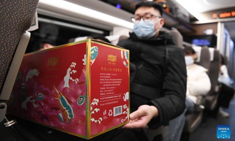 A passenger shows his New Year goods aboard train No.G9480 travelling from east China's Shanghai to Bozhou in east China's Anhui Province on the early morning of Jan. 14, 2023. The Hefei branch of China Railway Shanghai Bureau Group Co., Ltd. has added temporary night trains to meet the needs of travellers during the Spring Festival travel rush. (Xinhua/Zhang Duan)