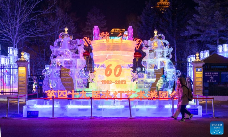 People pass the entrance of an ice lantern fair in Harbin, northeast China's Heilongjiang Province, Jan. 14, 2023. Harbin is famous for its rich ice and snow resources. This winter, the city opened three ice and snow-themed parks, launched 12 ice and snow experience products and 10 such tourism routes, and created more than 100 related activities to promote the development of winter tourism, culture, fashion and sports. (Xinhua/Xie Jianfei)