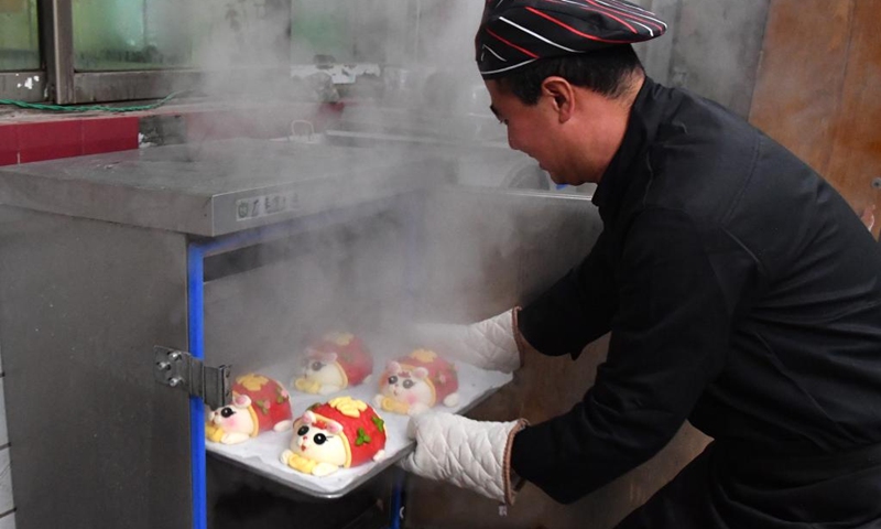 A pastry chef takes out finished rabbit-inspired steamed buns in Luoyang, central China's Henan Province, Jan. 13, 2023. A pastry workshop in Luoyang has introduced rabbit-inspired steamed buns in celebration of the upcoming Chinese Year of the Rabbit. (Xinhua/Li Jianan)