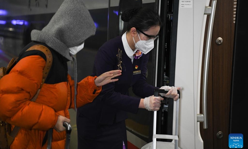 Wang Hao (R), crew member of train No.G9480, helps a passenger get on the train at Hefei Railway Station in Hefei, east China's Anhui Province, on the early morning of Jan. 14, 2023. The Hefei branch of China Railway Shanghai Bureau Group Co., Ltd. has added temporary night trains to meet the needs of travellers during the Spring Festival travel rush. (Xinhua/Zhang Duan)