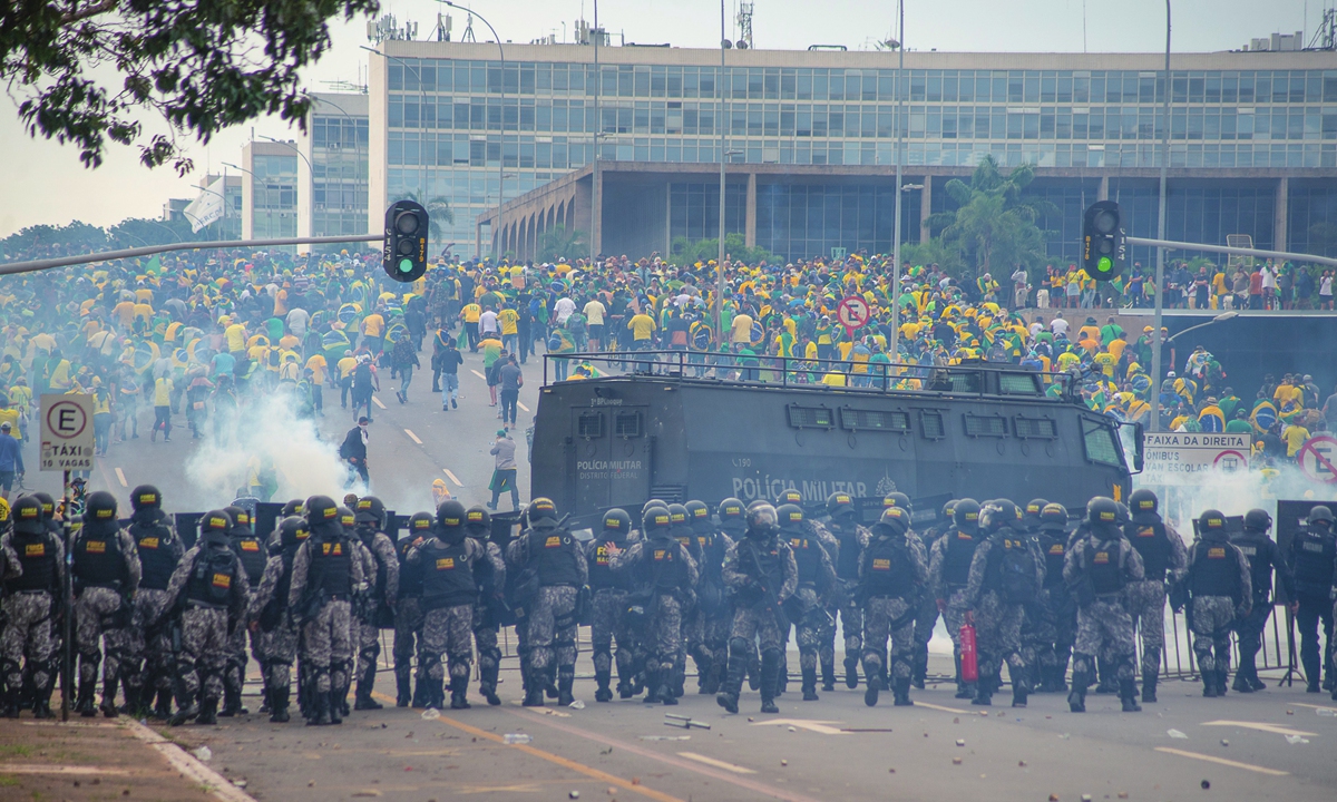 Supporters of former Brazilian President Jair Bolsonaro (back) clash with law enforcement officers in Brasilia, Brazil on January 9, 2023. The law-enforcement troops form a chain behind barriers and fire tear gas grenades at the demonstrators. An armored water cannon is also deployed. Photo: IC