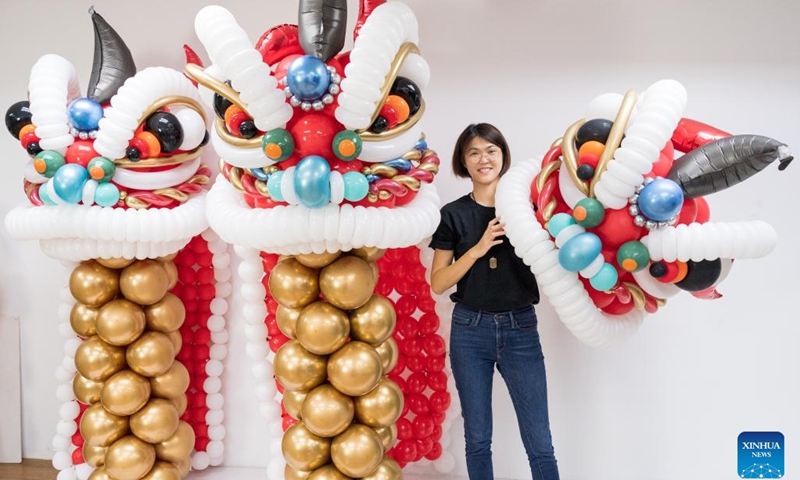 Syndy Tan Sing Yit poses for a photo with the lion dance balloon sculptures in her workshop near Kuala Lumpur, Malaysia, Dec. 31, 2022. Syndy Tan Sing Yit is a Malaysian balloon stylist who has been working on balloon modeling for more than a decade. She has created lion dance balloon sculptures by referring to lion dance graphics and pictures. (Photo: Xinhua)