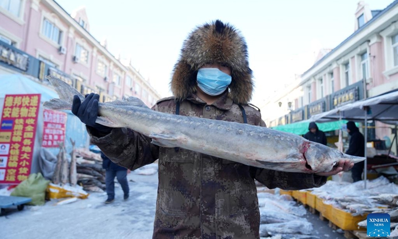 A fishmonger displays a fish at Dongji fish market, literally meaning the easternmost fish market, in Fuyuan City, northeast China's Heilongjiang Province, Jan. 9, 2023. As the Spring Festival approaches, Dongji fish market in Fuyuan has entered its peak season, with daily online sales exceeding 300,000 yuan (about 44,307 U.S. dollars).(Photo: Xinhua)