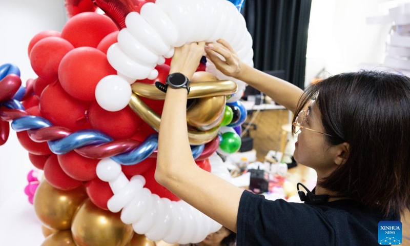 Syndy Tan Sing Yit adjusts a lion dance balloon sculpture in her workshop near Kuala Lumpur, Malaysia, Jan. 11, 2023. Syndy Tan Sing Yit is a Malaysian balloon stylist who has been working on balloon modeling for more than a decade. She has created lion dance balloon sculptures by referring to lion dance graphics and pictures.(Photo: Xinhua)