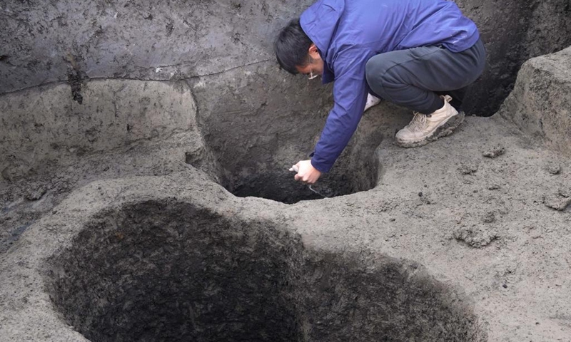 An archaeologist uncovers ash pits at a relic site in Shangqiu, central China's Henan Province, Jan. 6, 2023. Archaeologists in central China's Henan Province have uncovered a sprawling layer of mulberry and cypress branches, believed to be the foundation of an ancient city wall. Covering an area of nearly 400 square meters in the city of Shangqiu, the branches are dated to the Song Dynasty (960-1279), according to the city's institute of cultural relics and archaeology.(Photo: Xinhua)