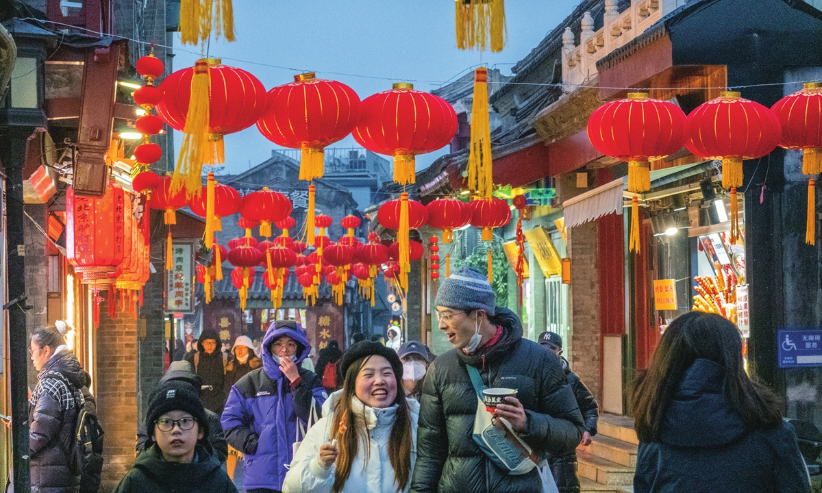 Tourists go shopping and enjoy the festive atmosphere on Yandaixie Street at Houhai, a scenic spot in Beijing on January 12, 2023. Photo: VCG