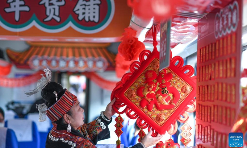 A passenger selects New Year decorations on train No. 5640 in southwest China's Guizhou Province, Jan. 10, 2023. The pair of slow trains No. 5640 and No. 5639 run in Guizhou Province between Yuping Dong Autonomous County of Tongren City and Guizhou's capital Guiyang City. The trains pass through several townships in Qiandongnan Miao and Dong Autonomous Prefecture, connecting more than 100 ethnic minority villages along the 337-km route.(Photo: Xinhua)