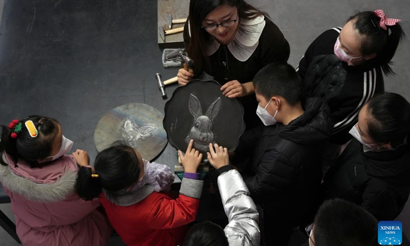 An artist displays a rabbit-themed relief to children at a cultural studio in Xinhua District of Shijiazhuang, north China's Hebei Province, Jan. 12, 2023. Cultural activities promoting intangible cultural heritages were held in Xinhua District to greet the upcoming Chinese Lunar New Year.(Photo: Xinhua)